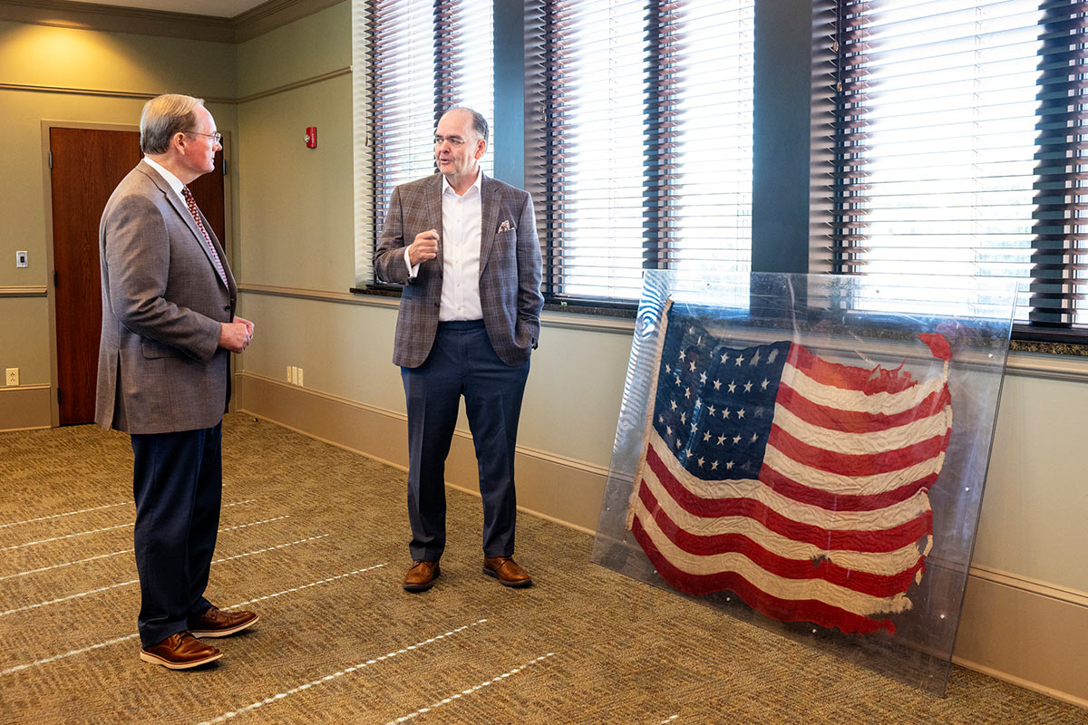 Two men discussing vintage flag showing wear and tear