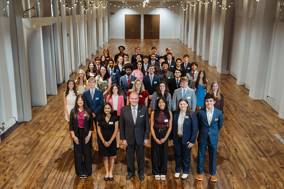 Students in a group photo with older gentleman in hallway