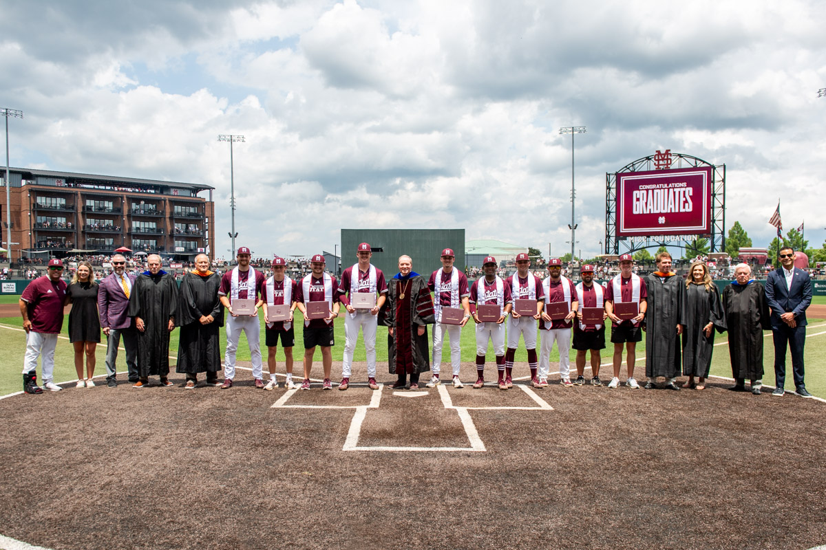 MSU President Mark E. Keenum and members of the Mississippi Institutions of Higher Learning Board of Trustees stand with graduat