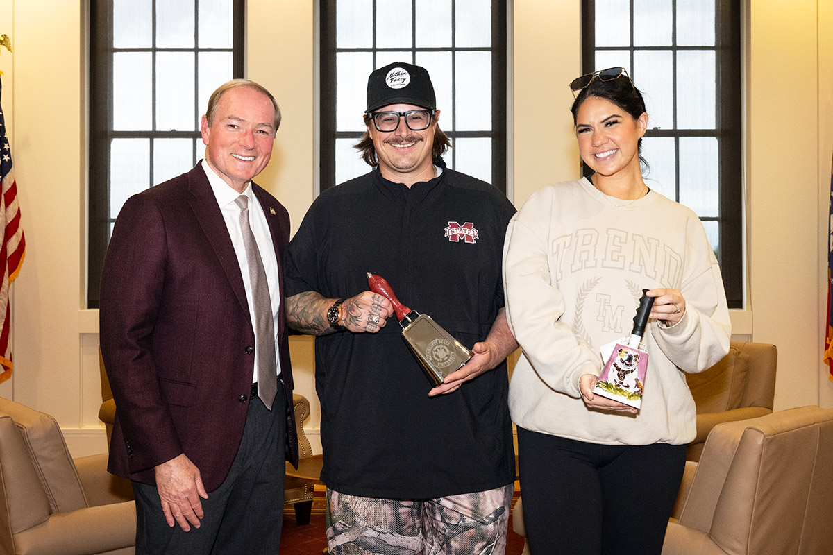 MSU President Mark E. Keenum presents country singer Michael Wilson Hardy and his wife, Caleigh Ryan, with a cowbell